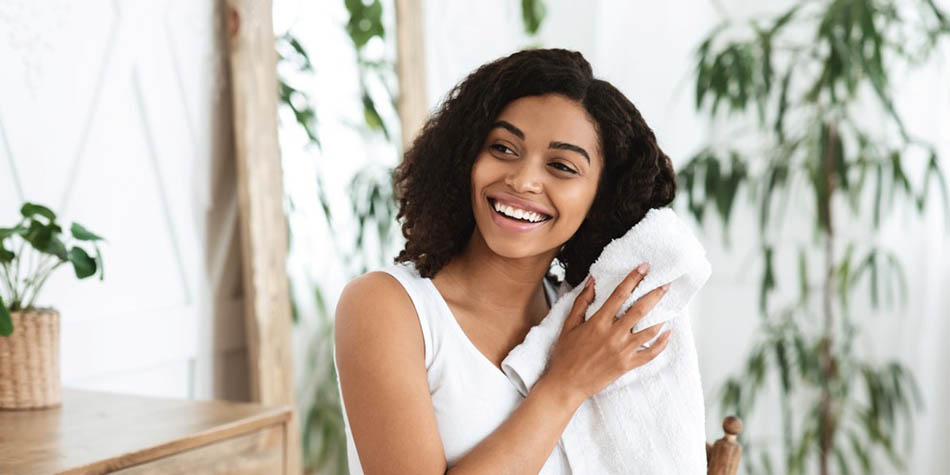 A woman dries her hair with a towel.